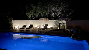 A swimming pool with lounge chairs and a swan float. - Beautiful waterfront villa (Porto-Vecchio)