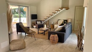 A spacious living room with a black sofa, a coffee table, and a staircase leading to an upper floor. - Beautiful waterfront villa (Porto-Vecchio)