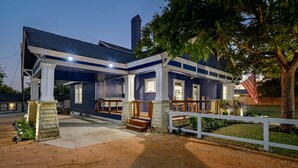 Una casa de dos pisos con un porche cubierto y un patio cercado.