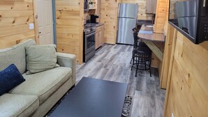 A compact kitchen with wooden paneling, a stainless steel refrigerator, a microwave, and a gas stove. - Adorable garden level condo with courtyard and firepit (Rutherfordton)