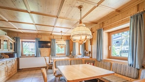 Een houten hut met een eethoek, banken en een televisie.