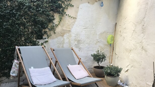 Two lounge chairs with cushions, a potted plant, and a wall with peeling paint. - Studio Avec Jardin (Marseille)
