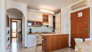 Una cucina compatta con isola centrale, pensili integrati e un'area pranzo con tavolo.