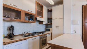 Una cucina funzionale con lavastoviglie, piano cottura, forno a microonde e pensili in legno.