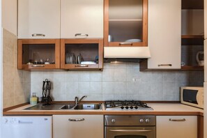 Une cuisine équipée d’une cuisinière à gaz, d’un four à micro-ondes et de placards aux portes en verre.