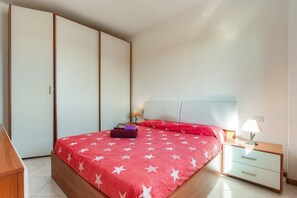 Une chambre à coucher comprenant un lit, une table de chevet, une lampe, une armoire et une commode.