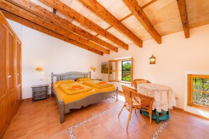 Un dormitorio con cama, mesitas de noche, una silla, una mesa y una ventana con vistas.