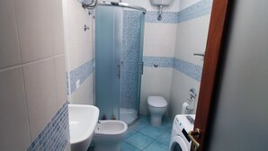 Ein Badezimmer mit Toilette, Bidet, Waschbecken und einer Waschmaschine.