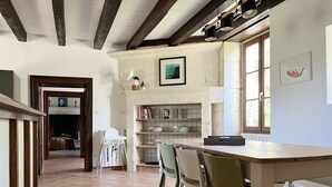 Een rustieke keuken met een houten tafel en stoelen, een betegelde spatwand en een raam met natuurlijk licht.