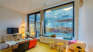 Eine moderne Küche mit einem großen Fenster, einem Essbereich mit Fernseher und einem kleinen Tisch mit Barhocker.
