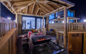 An outdoor patio with a grill, dining table, and chairs.