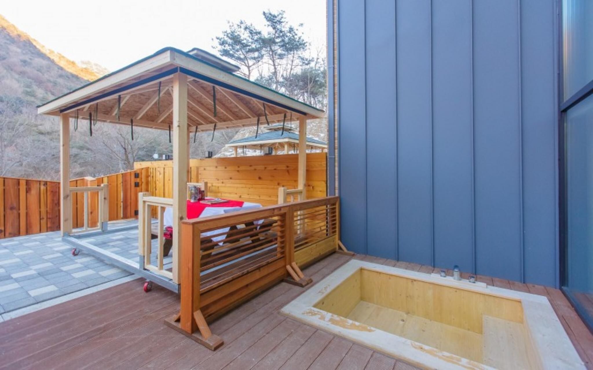 A wooden deck with a covered seating area and a hot tub.