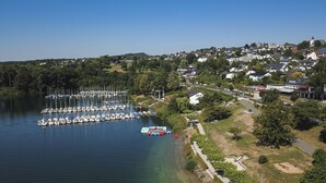 Een jachthaven met talloze boten die aanmeren, een klein gebied voor bootverhuur, en een woonwijk met huizen en groen op de achtergrond.