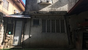 A rustic building with a corrugated metal roof, a small porch, and a window with a metal grill. - Stay in resedential house in pasig city (Pasig)
