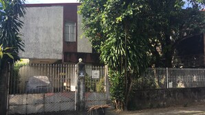 A building with a concrete facade, a metal gate, and a tree in front. - Stay in resedential house in pasig city (Pasig)