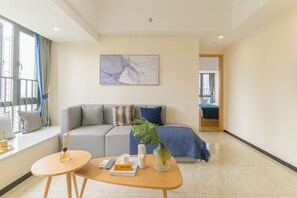 Ein modernes Wohnzimmer mit einer Couch, einem Couchtisch, einer Pflanze und einem Gemälde an der Wand.