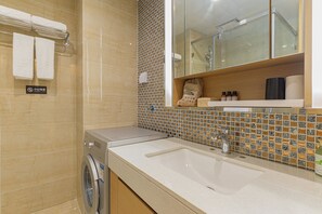 A hotel bathroom with a washing machine, a sink, and a tiled backsplash.