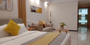 Ein Hotelzimmer mit Bett, einer Couch, einem kleinen Tisch mit Pflanze und einem Bild an der Wand.