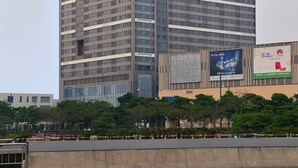 A tall, modern skyscraper with a grid of windows and a prominent sign at the top. - Bainianhui International Apartment (Foshan)