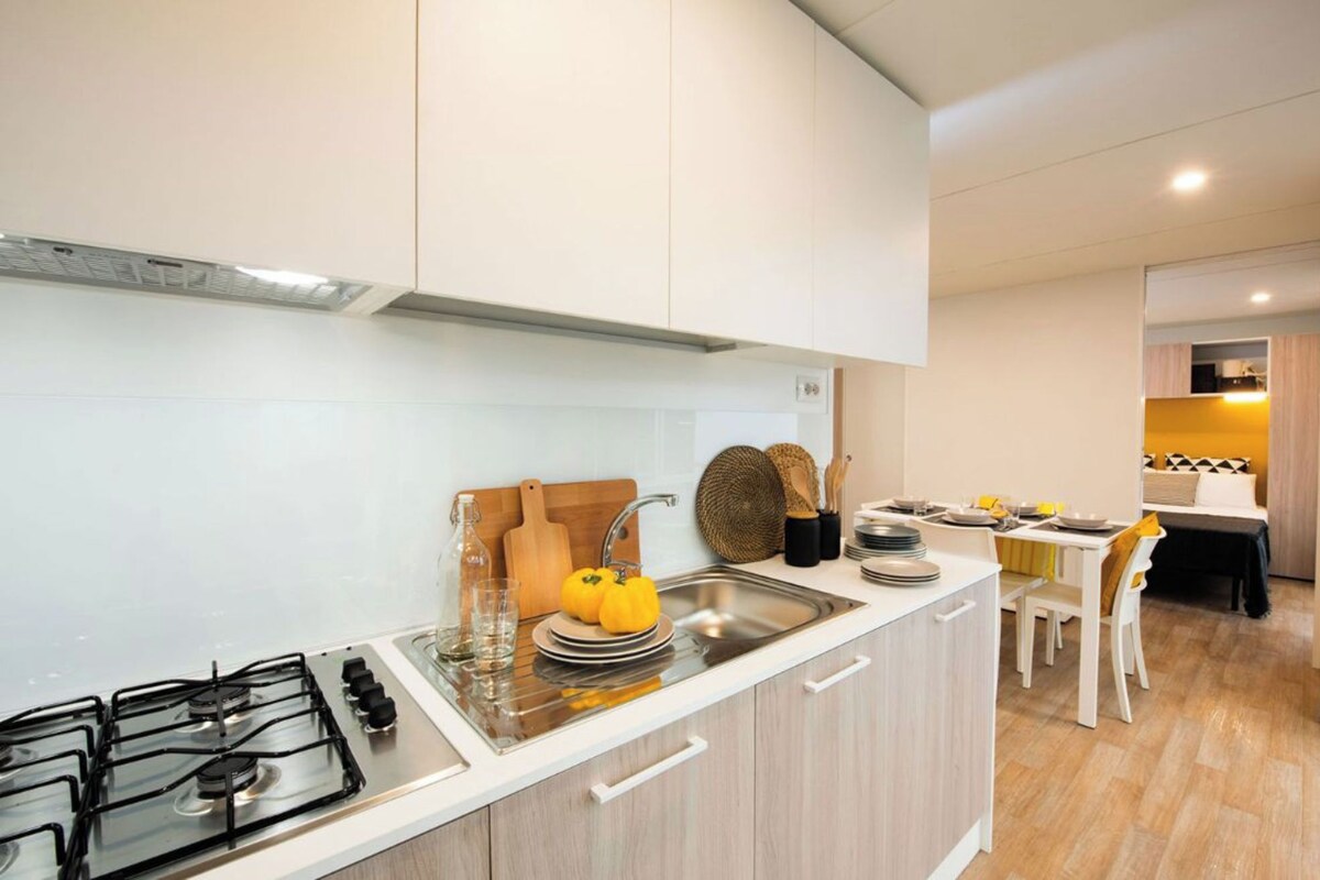 A modern kitchen with a gas stove, a sink, and a dining area with a table and chairs.