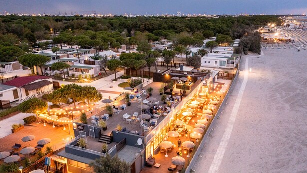 A coastal hotel with outdoor seating areas, a beach view, and a row of cabins. - Club Del Sole Pini Boutique Resort (Ravenna)