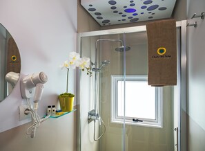 A modern bathroom with a hairdryer, a potted orchid, and a shower with a glass door. - Club Del Sole Pini Boutique Resort (Ravenna)
