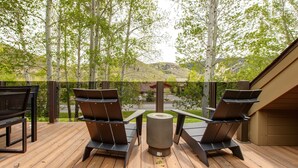 A deck with two chairs and a table, overlooking a scenic landscape with trees and hills. - Step into Your Luxury Condo Today - Hot Tub & Wi-Fi Access! (Park City)