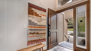A wooden bench, a woven rug, and a door with a glass panel. - Step into Your Luxury Condo Today - Hot Tub & Wi-Fi Access! (Park City)