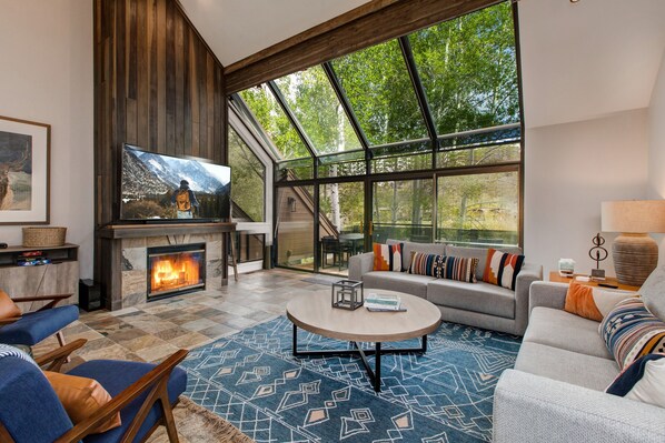 A modern living room with a fireplace, large windows, and a cozy seating area.