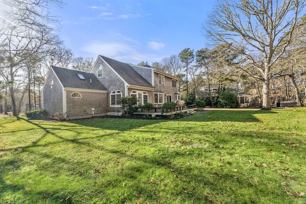 Une maison à deux étages avec un grand jardin devant, une véranda et un garage.