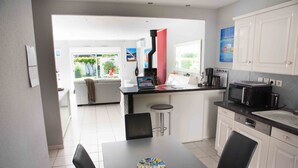 A modern kitchen with white cabinets, a black countertop, and a dining area with a table and chairs. - HOUSE, CONTEMPORARY COMFORT AND TRANQUILITY 15 MINUTES FROM THE BEACH  (Mauguio)
