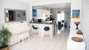 A modern kitchen with white cabinets, a central island with stools, and a dining area with chairs. - HOUSE, CONTEMPORARY COMFORT AND TRANQUILITY 15 MINUTES FROM THE BEACH  (Mauguio)