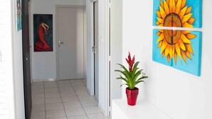 A hallway with white walls, a tiled floor, a door, and two paintings of sunflowers. - HOUSE, CONTEMPORARY COMFORT AND TRANQUILITY 15 MINUTES FROM THE BEACH  (Mauguio)