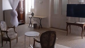 Un salón amplio con un televisor grande, muebles elegantes y un techo decorativo.