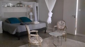 Un dormitorio con cama, dos sillas, una mesita de noche y dosel.