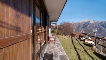 Un bâtiment en bois avec une terrasse en pierre, une chaise et une vue sur les montagnes.
