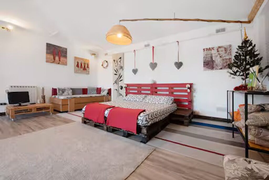Een kamer met een bed, een televisie, een bank en een kleintje tafel met een kerstboom.