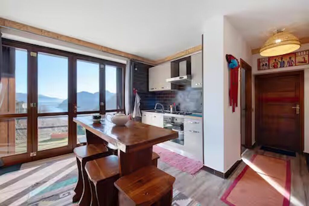 Een moderne keuken met grote ramen, een eethoek met een houten tafel, en uitzicht op de bergen.
