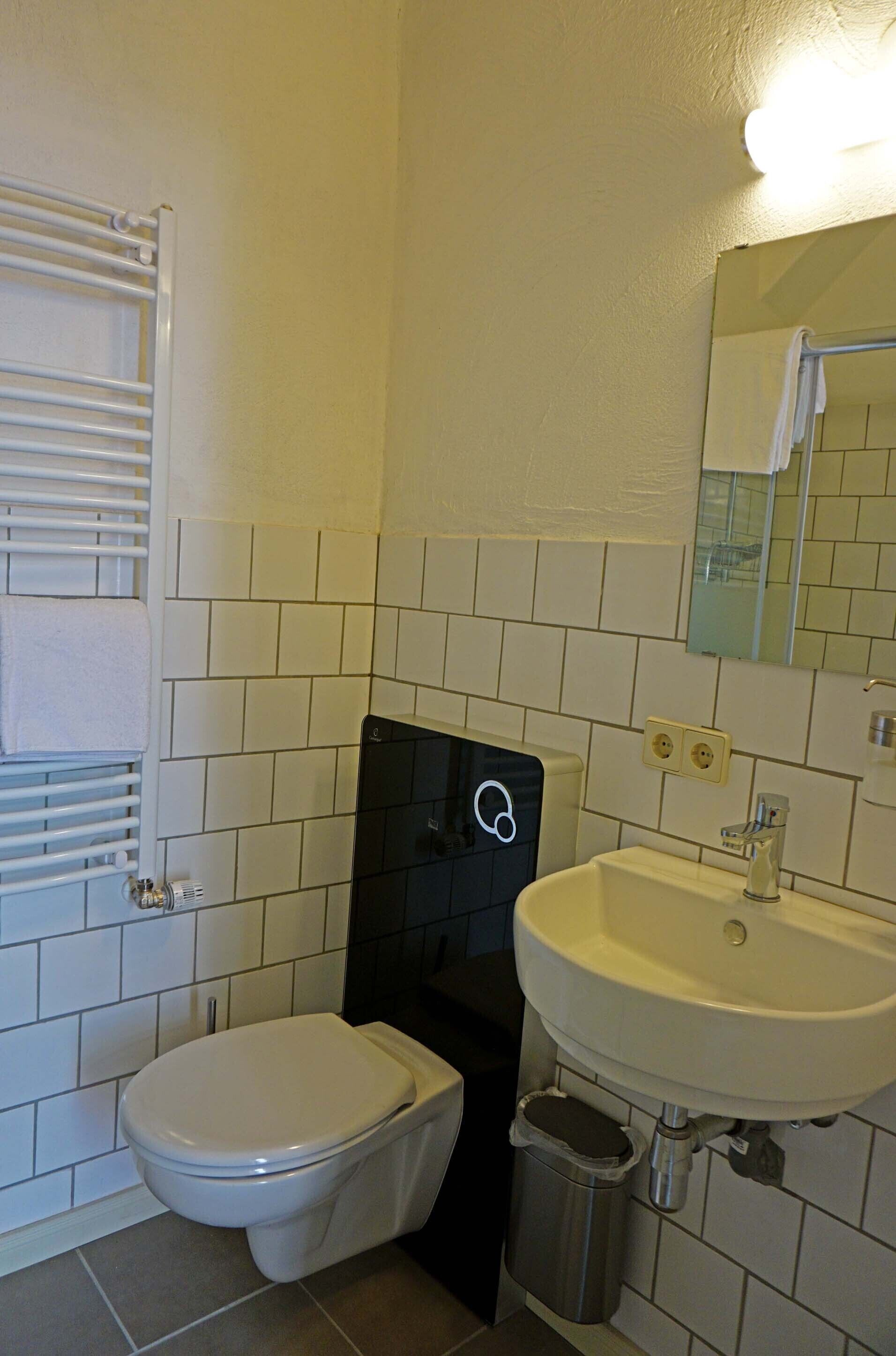A small bathroom with a toilet, sink, and mirror.