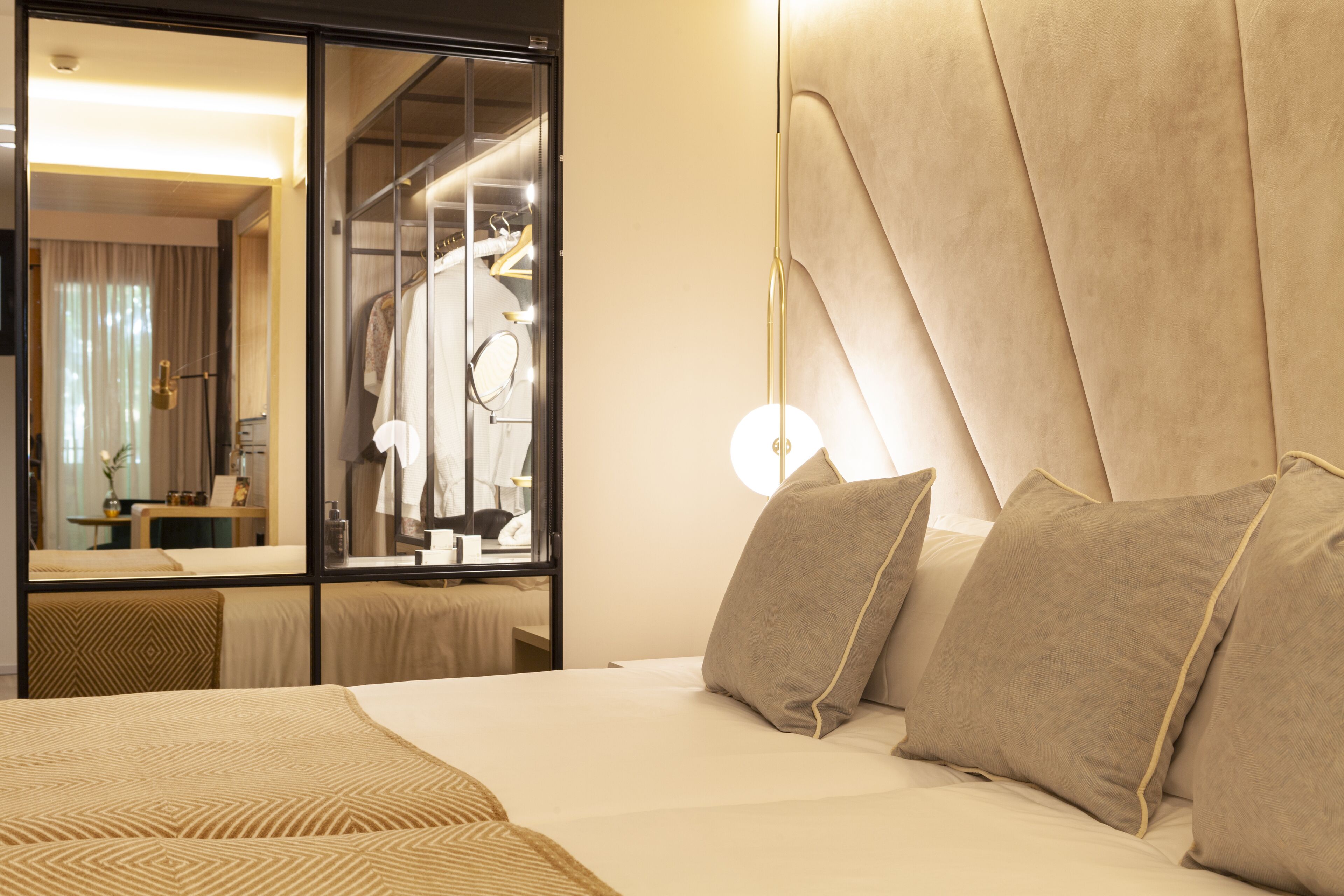 A hotel room with a large bed, a mirror, and a wardrobe.