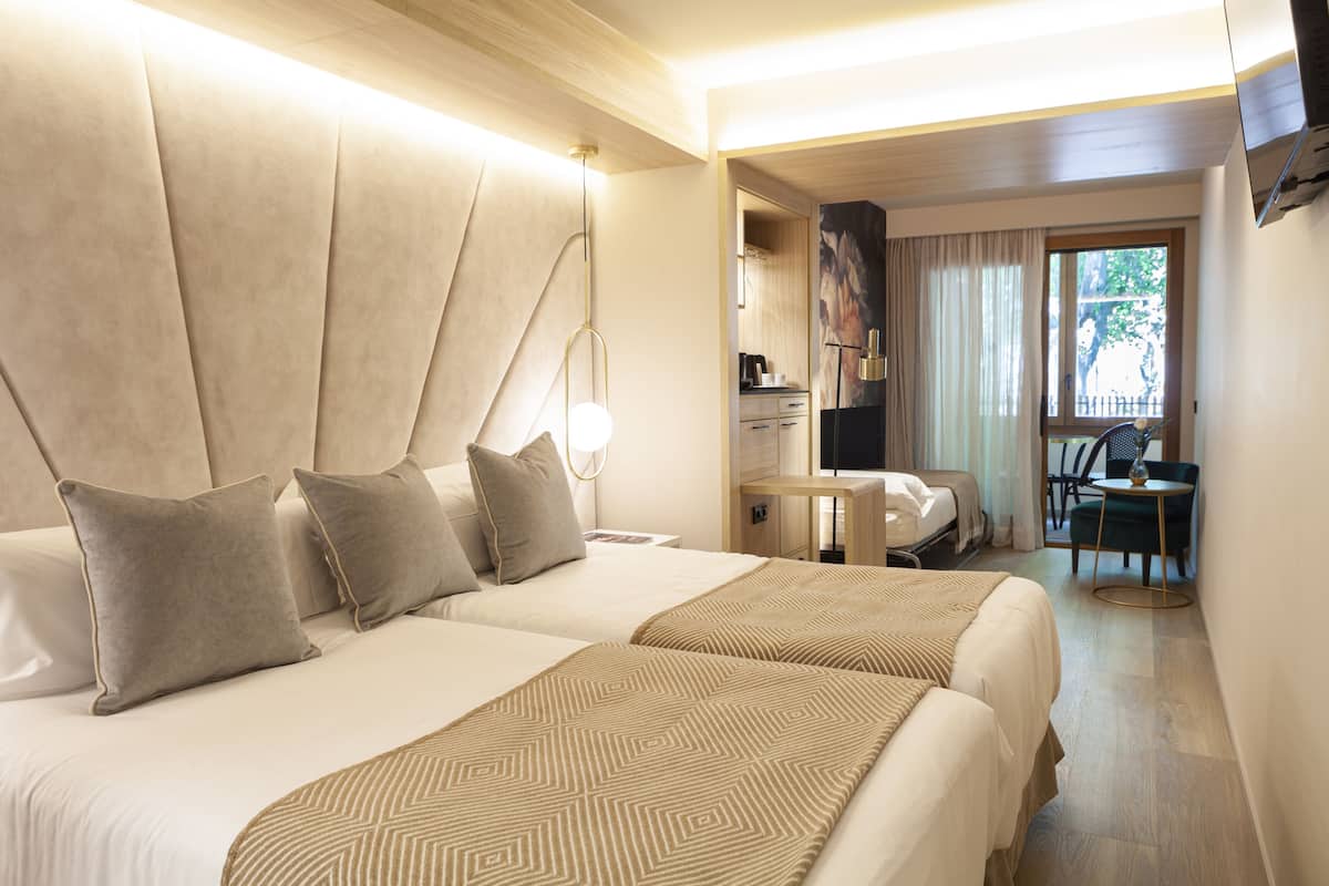 Hotelkamer met twee bedden, een kleine kitchenette, een eethoek en uitzicht op de omgeving.