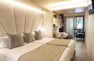 Habitación de hotel con dos camas, una kitchenette pequeña, un área de comedor y vistas al exterior.