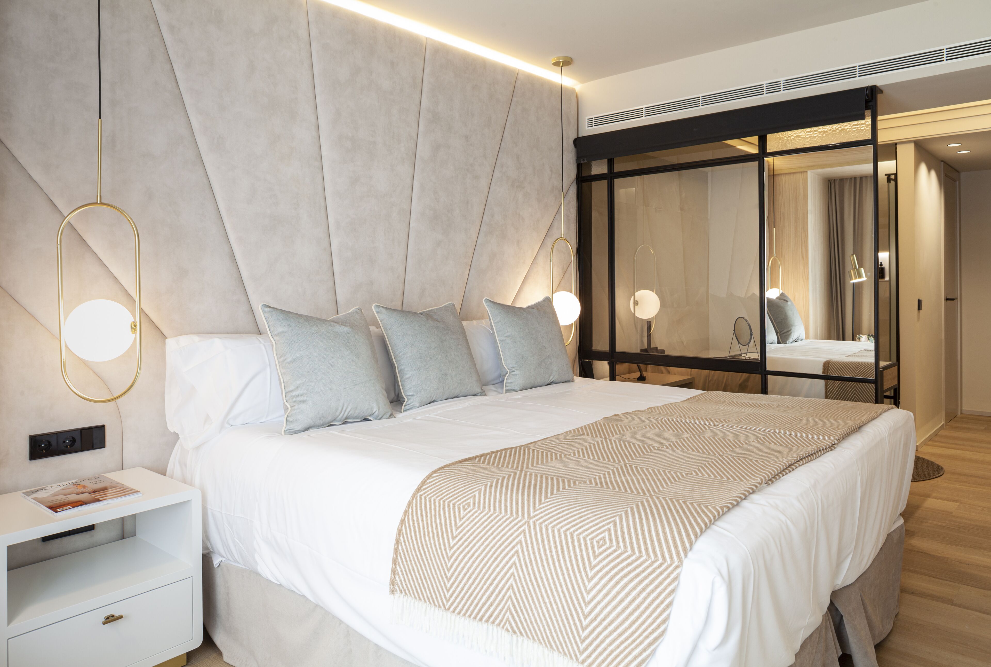 Un dormitorio moderno con una cama grande, mesitas de noche y un espejo.