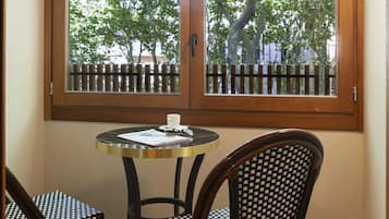 Habitación de esquina con ventana, dos sillas y una mesita.
