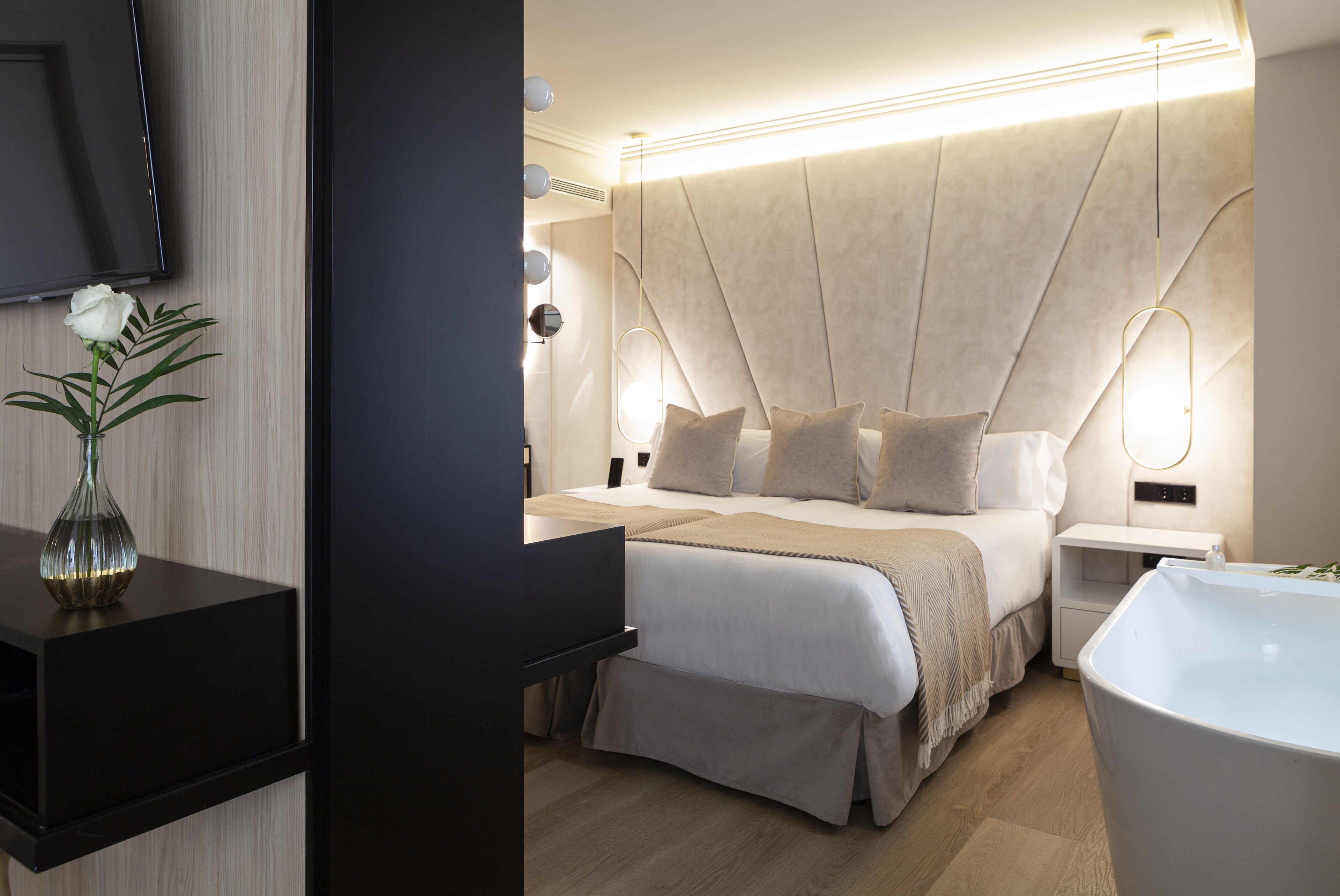 Un dormitorio moderno con una cama grande, mesitas de noche, un televisor y una bañera.
