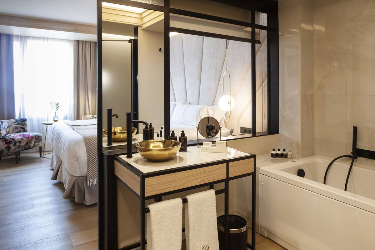 Een moderne badkamer met een grote spiegel, een badkuip en een wastafelmeubel met een wastafel.