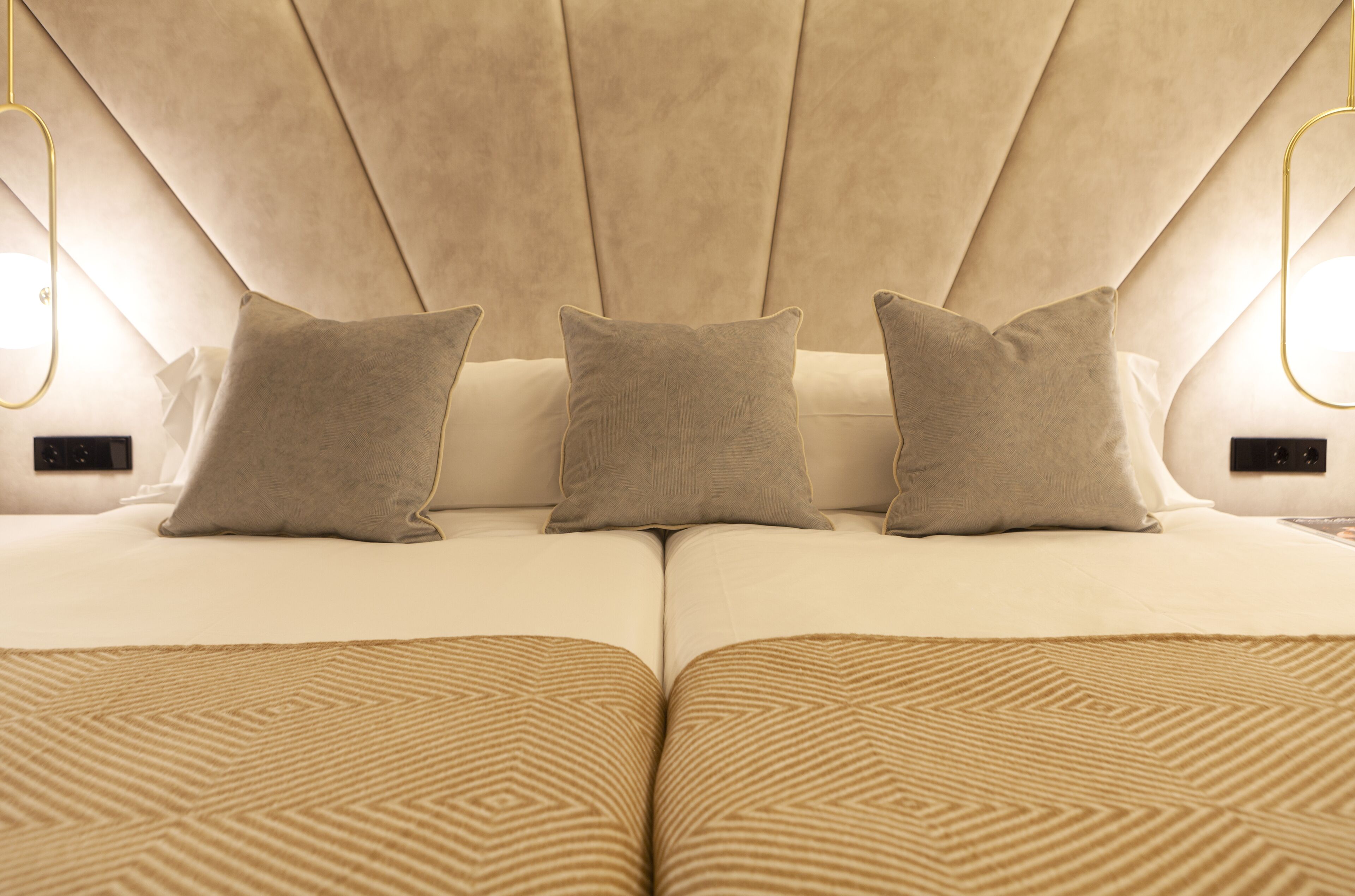Un lit doté d’une tête de lit capitonnée, de trois oreillers et d’une couvre-lit à motifs.