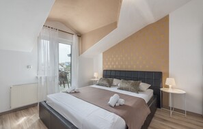 Moderni hotellihuone, jossa on suuri sänky, parveke ja näkymä kaupunkiin.