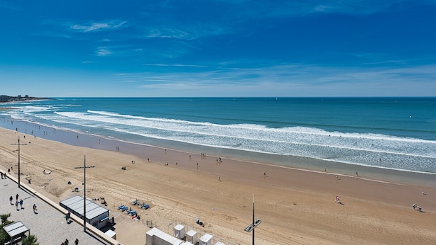 Ein Strand mit breitem Sandstrand, blauem Himmel und ruhiger See.