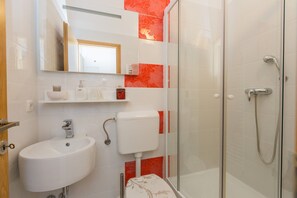Une salle de bain moderne avec une douche à parois de verre, un lavabo blanc et des toilettes.